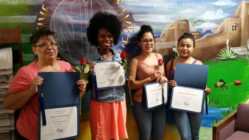 Four graduates from the Personal Care Aide program display their diplomas.